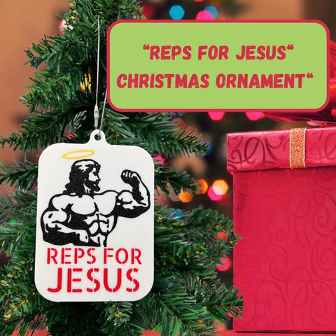 A Christmas tree displays the Chatelet Manufacturing “Reps for Jesus Weightlifting Christmas Ornament,” featuring a muscular, haloed figure. Nearby are a red gift and a “‘Reps for Jesus’ Christmas Ornament” sign. Made in USA.