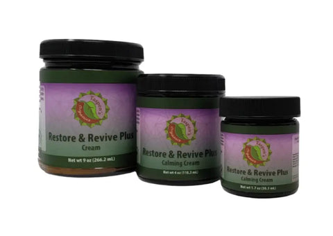 Three jars of Taspens Organics Restore & Revive Calming Cream PLUS, each in a different size with green and purple labels and black lids, arranged in a row on a white background.
