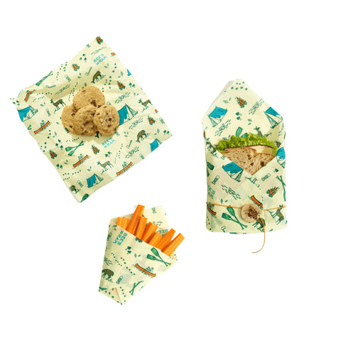 The Lunch Pack by Bee’s Wrap includes three washable, reusable wraps with camping prints for cookies, carrot sticks, and a sandwich. Perfect for keeping snacks fresh and eco-friendly. Shown arranged on a white background.