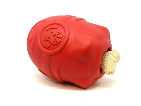 The SodaPup Rocketman Durable Rubber Treat Dispenser & Chew Toy is a tough red barrel with a dog face design, holds a bone-shaped treat at one end, and offers fun and rewarding play for your pup. Shown against a white background.