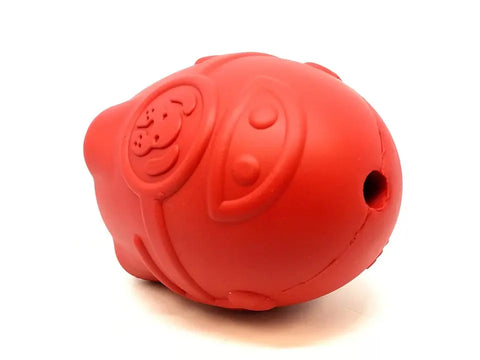 The SodaPup Rocketman Durable Rubber Treat Dispenser & Chew Toy is a red, oval-shaped chew toy with embossed patterns, featuring a cartoon dog face and eyes, plus a treat-dispensing hole at one end, shown on a white background.