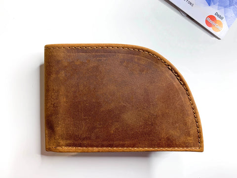 The Rogue Industries Rogue Front Pocket Wallet in Allagash Tan premium top grain leather, featuring visible stitching, rests on a white surface with a MasterCard credit card partially visible at the top right corner.