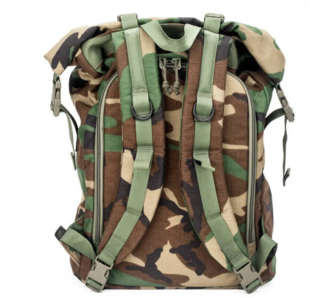 The MIS Roll Up Backpack - Woodland Camo features a Cordura Nylon build in green and brown camo, padded shoulder straps, side buckles, roll-top closure, and a YKK zipper. Shown upright with back and straps visible.