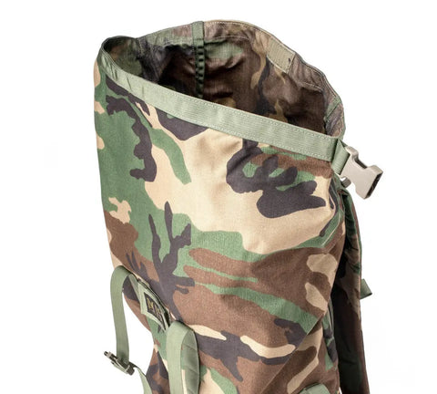 The MIS Roll Up Backpack - Woodland Camo features durable Cordura Nylon, green straps, an open top showing the interior, and a side plastic buckle—crafted for rugged use in a military-inspired design.