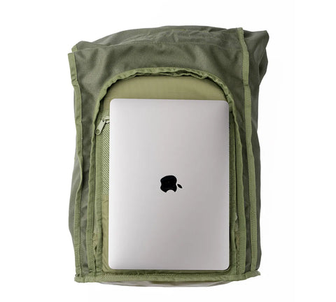 An open MIS Roll Up Backpack - Woodland Camo, made of Cordura Nylon with a heavy-duty YKK zipper, reveals a silver laptop with a black apple logo, partially tucked inside the main compartment.