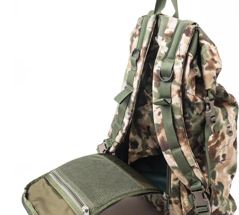 The MIS Roll Up Backpack - Covert Woodland, featuring a camouflage Cordura Nylon design with green straps and mesh pockets, is partially unzipped and displayed against a white background.