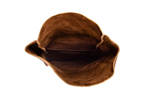 Top view of an empty weather-resistant Urban Southern Rolltop Backpack in brown suede with an open flap, revealing a soft interior and small inner pocket, set against a white background.