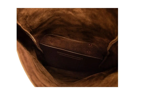 A close-up of the Urban Southern Rolltop Backpacks weather-resistant brown suede interior, highlighting a pocket and a slim item or divider within the main compartment.