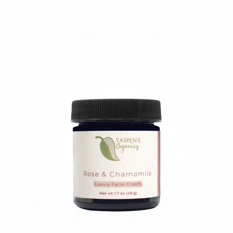 A dark blue jar with a black lid labeled Taspens Organics Rose & Chamomile Luxury Facial Cream, an organic moisturizer for sensitive skin, 1.7 oz (48 g), shown against a plain white background.