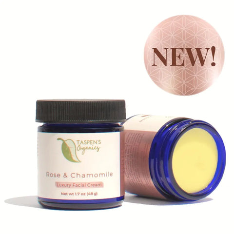 Two blue jars of Taspens Organics Rose & Chamomile Luxury Facial Cream, one upright and one open on its side, display this organic moisturizer for sensitive skin. A pink NEW! circle is in the upper right corner.