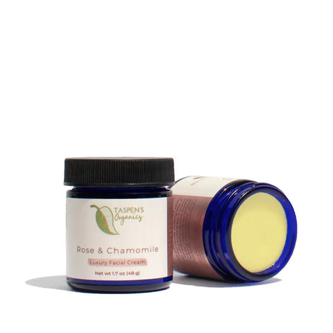 Two jars of Taspens Organics Rose & Chamomile Luxury Facial Cream are shown—one upright with its label visible, the other on its side with the lid off to display the gentle moisturizer inside.