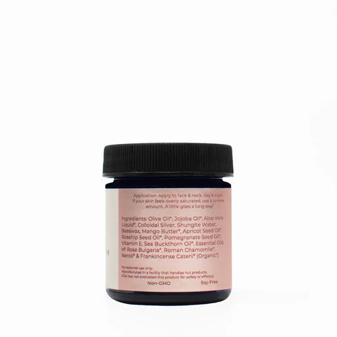 The Rose & Chamomile Luxury Facial Cream by Taspens Organics comes in a dark blue jar with a pink label featuring ingredients like olive oil, jojoba oil, aloe vera, and essential oils. This organic moisturizer is ideal for sensitive skin care. Set against a white background.