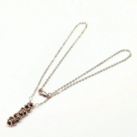 The Super Sparkly Crystal Rock Candy Beaded Rose Gold Crystal Bar Necklace by Alexa Martha Designs features a delicate gold chain and five faceted beads in a vertical bar, secured with a lobster clasp for an elegant, eye-catching look.