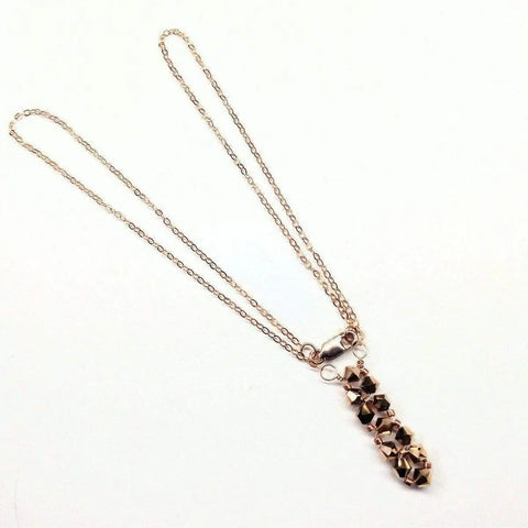 The Super Sparkly Crystal Rock Candy Beaded Rose Gold Crystal Bar Necklace by Alexa Martha Designs features a vertical row of faceted beads in a clustered design, displayed on a plain white background.