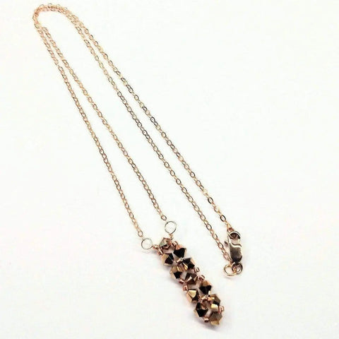 The Super Sparkly Crystal Rock Candy Beaded Rose Gold Crystal Bar Necklace by Alexa Martha Designs features a handcrafted bar pendant of faceted beads on a gold chain with a lobster clasp, shown on a white background.