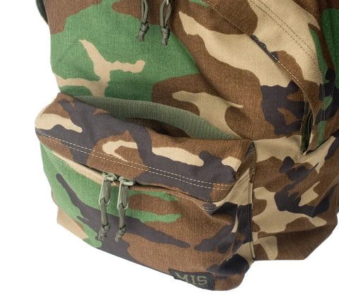 A close-up of the MIS Daypack Cordura - Woodland Camo, made from durable green, brown, and tan Cordura nylon, with a front zippered pocket.