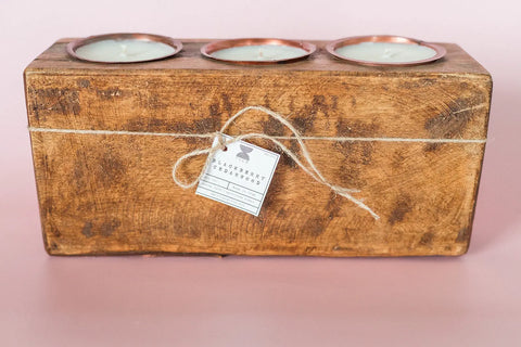The Shanti + Tula Rustic Wooden Sugar Mold Candle – 3-Hole Dough Bowl features clean-burning soy wax in copper cups, handmade in the USA, tied with twine and a tag for a charming, handcrafted touch.