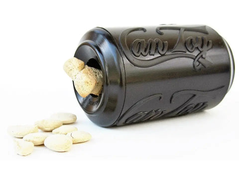 A black SP Magnum Can Toy EDispenser by SodaPup, made of ultra durable rubber, lies on its side with treats inside and spilling onto a white surface. Can Toy is embossed on this treat dispenser.