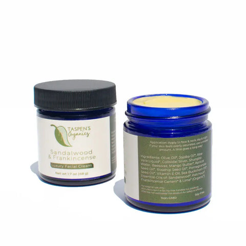 Two blue jars of Taspens Organics Sandalwood & Frankincense Luxury Facial Cream—one closed with the front label, one open to show the cream and ingredients—an American-made organic moisturizer.