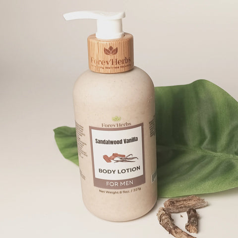 A bottle of Forev'Herbs Sandalwood Vanilla Lotion rests on a white surface next to a green leaf and wood. The moisturizing lotion features a wooden cap and beige label displaying product details.