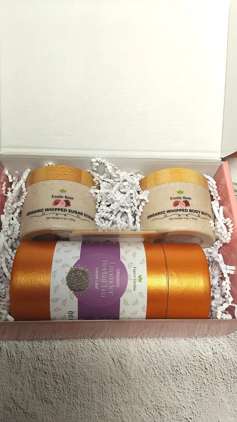 The Forev'Herbs Self-Care Gift Set with white crinkle paper includes Rose Sugar Scrub and Organic Whipped Body Butter jars, plus an orange container of Organic Flower Infused Face Mist – Rosewater.