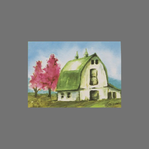 JuLu Cards Pack of 8 - Barn With Pink Trees (10008) features a watercolor of a white barn with a green roof and two blooming pink trees under a blue sky. Each card fits 3.5 x 5 and is signed by the artist in the bottom right corner.