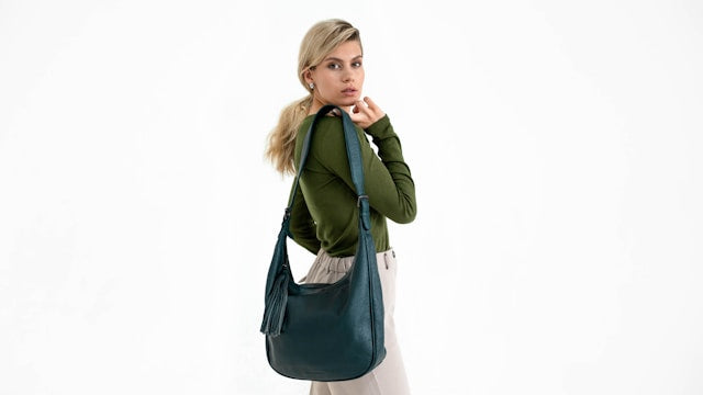 Woman holding a blue shoulder bag against a white background