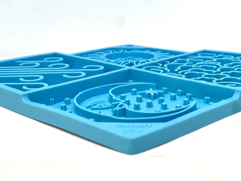 A close-up of the Sky Design EMat Enrichment Lick Mat by SodaPup, a blue silicone sensory pad with four textured sections and raised shapes for tactile stimulation, shown on a white background.