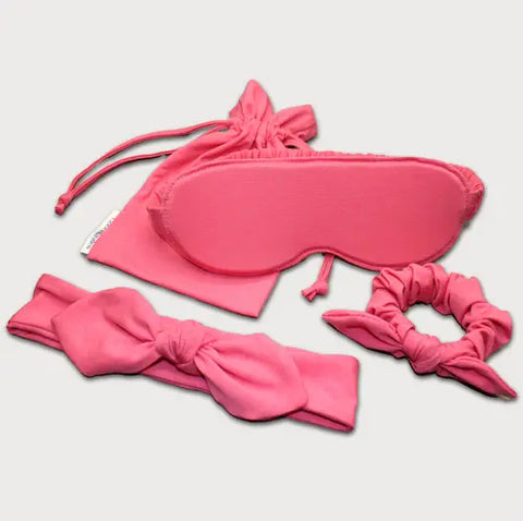 The Goodnighties Accessories Value Pack features pink sleepwear essentials—a sleep mask, drawstring pouch, bow headband, and scrunchie—beautifully arranged on a light background.
