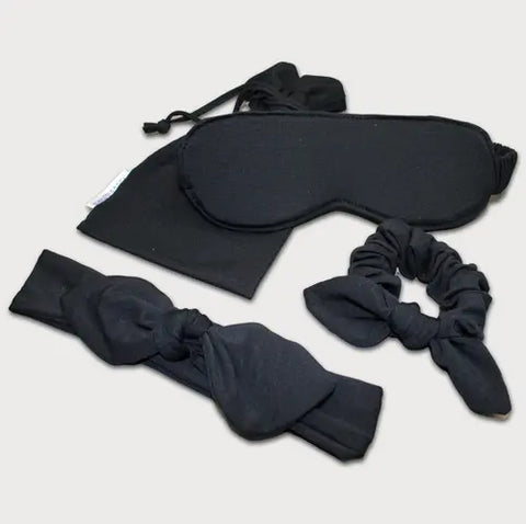 The Goodnighties Accessories Value Pack features black sleepwear essentials—a sleep mask, drawstring pouch, knotted headband, and scrunchie with bow—beautifully arranged on a light background.