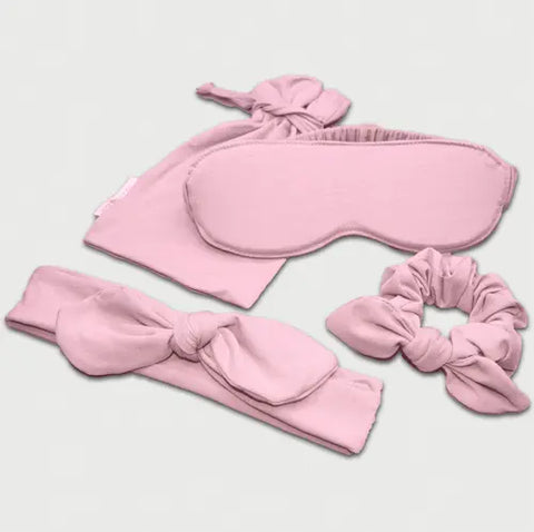 The Goodnighties Accessories Value Pack includes pink fabric sleepwear essentials—a sleep mask, drawstring pouch, knotted headband, and scrunchie—arranged on a light background.