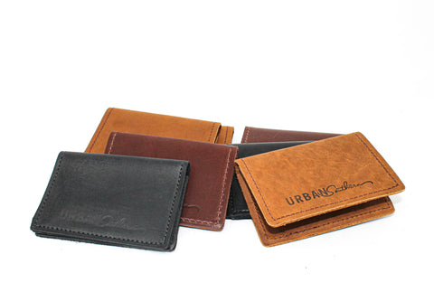 Five leather wallets in black, brown, and tan are arranged on a white background. In the front right is a tan Urban Southern Bifold Card Wallet featuring printed URBAN and cursive branding.