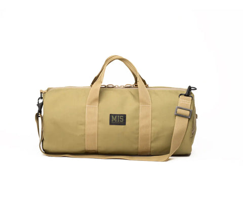 The MIS Training Drum Bag Small in Coyote Tan is a USA-made, water-resistant duffel with two short handles, a detachable shoulder strap, and a front MIS patch, shown against a plain white background.