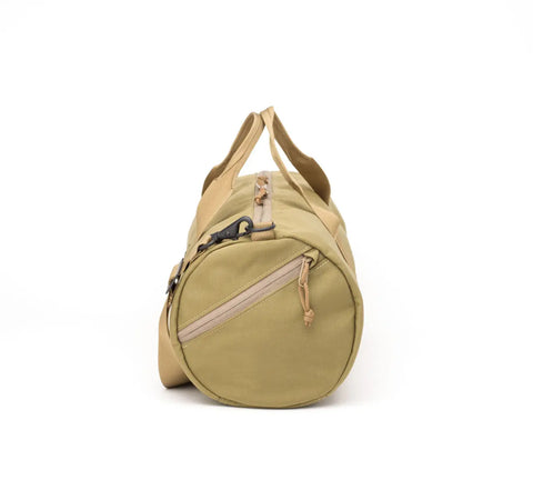 The MIS Training Drum Bag Small in Coyote Tan is shown from the side against a white background, featuring rugged Cordura nylon, round end zip pocket, webbing handles, and a shoulder strap—all made in the USA.