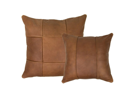 Two brown full-grain leather pillows—one an American-made square patchwork throw pillow, the other the Urban Southern Small Leather Pillow with two vertical stitched seams—displayed against a white background.