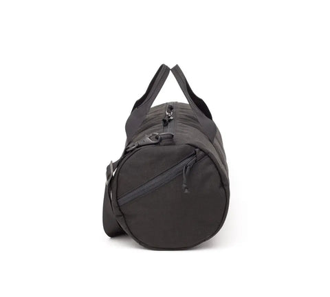 The MIS Training Drum Bag Small - Black is a cylindrical duffel crafted from 1000D Dupont Cordura Nylon with a YKK zipper, zippered side pocket, carrying handles, and adjustable shoulder strap, shown upright against a white background.