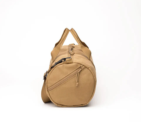The MIS Training Drum Bag Small in coyote brown is a water-resistant canvas duffel with a zipper closure, shoulder strap, and two handles, shown standing upright on one circular end against a plain white background.