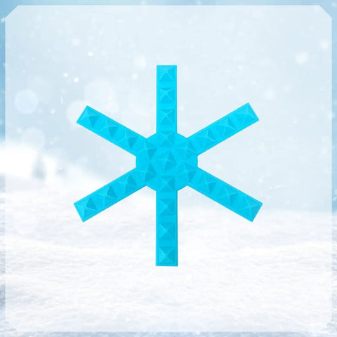 The Chatelet Manufacturing Snowboard Stomp Pad features a bright blue snowflake spike pattern, designed for superior grip and adhesion to your snowboard, standing out against the snowy backdrop.