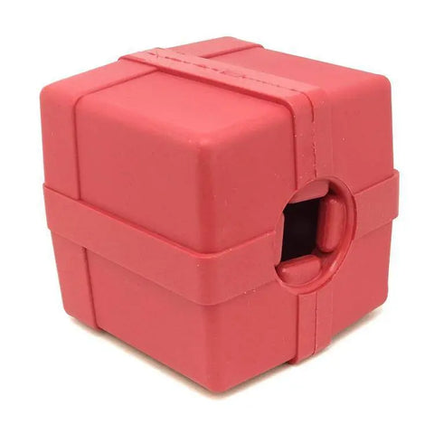 The SodaPup Gift Box EDispenser is a durable red rubber cube-shaped chew toy and treat dispenser with beveled edges, a circular indentation on one side, and two raised bands wrapping around the cube.