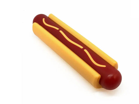 The SodaPup Hot Dog Ultra Durable Nylon Dog Chew Toy features a yellow bun, red sausage, and mustard-like squiggly line—made to reduce problem behaviors—with a plain white background.