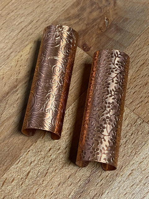 Two solid brass keychain holders with dial protection, made in the USA by Tallac House, feature a brass ring and rest on a wooden surface.