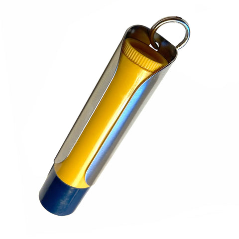 The Tallac House Lip Balm Solid Metal Keychain Holder with dial protection, made in USA, holds a yellow tube with blue cap and includes a keyring. Product shown isolated on white background.