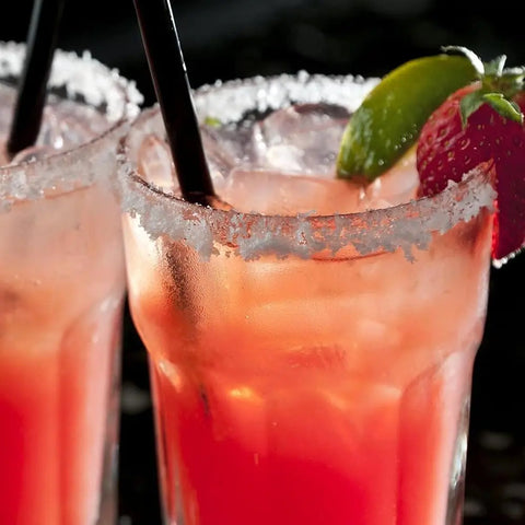 Two pink cocktails with ice, smoked sea salt from the Spicy Salts for Spring - 3 Pack Collection by vendor-unknown on the rims, garnished with lime and strawberry, each with a black straw. Drinks are chilled and refreshing.