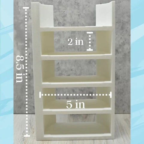 The Chatelet Manufacturing Lid Organizer holds 5 Stanley Cup lids and straws on four white shelves (8.5 tall, 2 shelf height, 5 shelf width), perfect for cabinets or counters. Shown on a light wood surface with a gray-blue background. Made in USA.