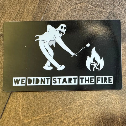 The Sticker: Start the Fire by American Lictor is a 3 x 4 sticker showing a cartoon ghost roasting marshmallows over a fire with WE DIDNT START THE FIRE text, unique flames details, and a dark wood backdrop.