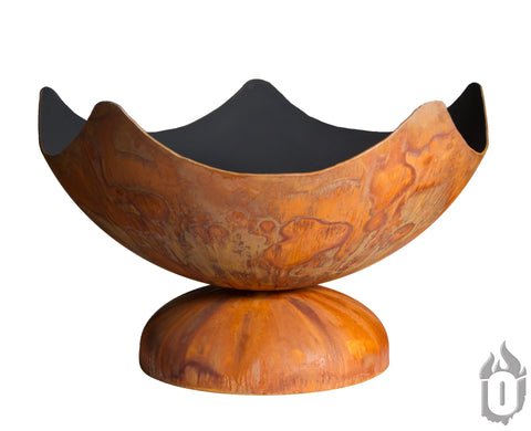 The Stellar Artisan Fire Bowl by Ohio Flame is a large, rust-colored carbon steel fire pit with a scalloped, bowl-shaped design on a rounded pedestal, featuring natural weathered patterns. Made in the USA.