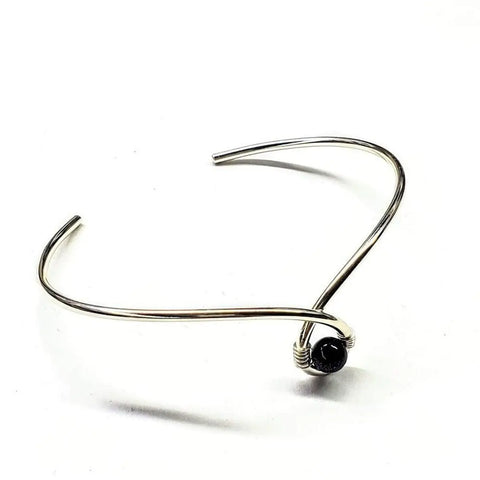 The Alexa Martha Designs Sterling Silver Blue Bead Ribbon Child Abuse Awareness Teardrop Bangle features a minimalist design with a blue bead accent, shown on a white background.