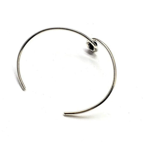 The Sterling Silver Blue Bead Ribbon Child Abuse Awareness Teardrop Bangle by Alexa Martha Designs features a minimalist design with a blue bead accent, shown against a white background.