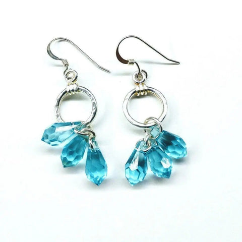 Sterling Silver Hammered Aqua Crystal Cascading Drop Earrings by Alexa Martha Designs feature handcrafted circular loops with three faceted blue Swarovski crystal teardrops, displayed on a white background.