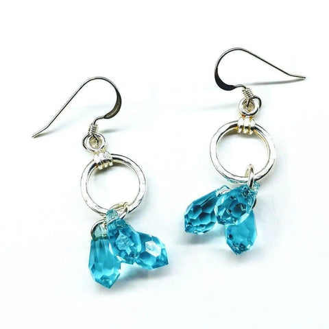 Sterling Silver Hammered Aqua Crystal Cascading Drop Earrings by Alexa Martha Designs feature circular loops with three faceted blue Swarovski crystal teardrops on each, shown on a white background.